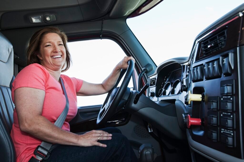 Caucasian woman driver in the cab of a commercial truck.